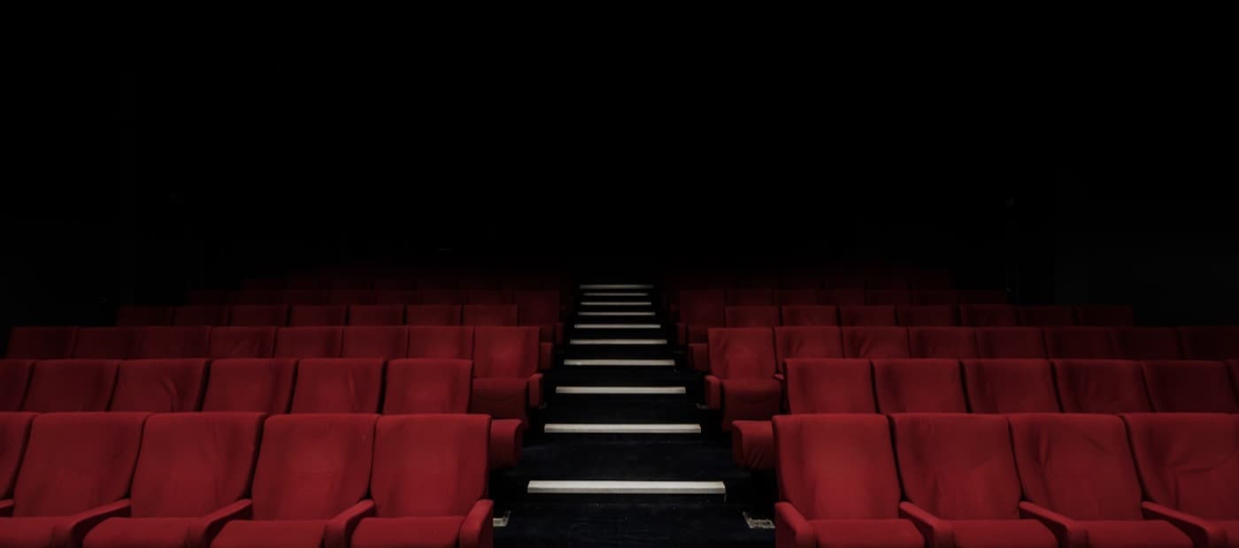 An empty cinema, red seats facing a dark screen