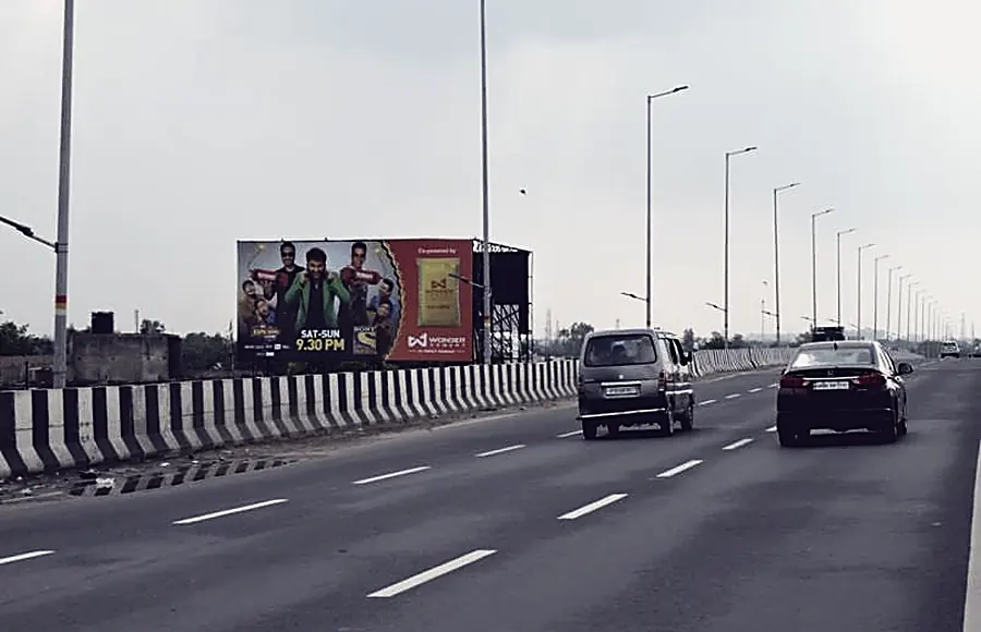 An Agra arterial at commute hour, a roadside hoarding and traffic on the carriageway