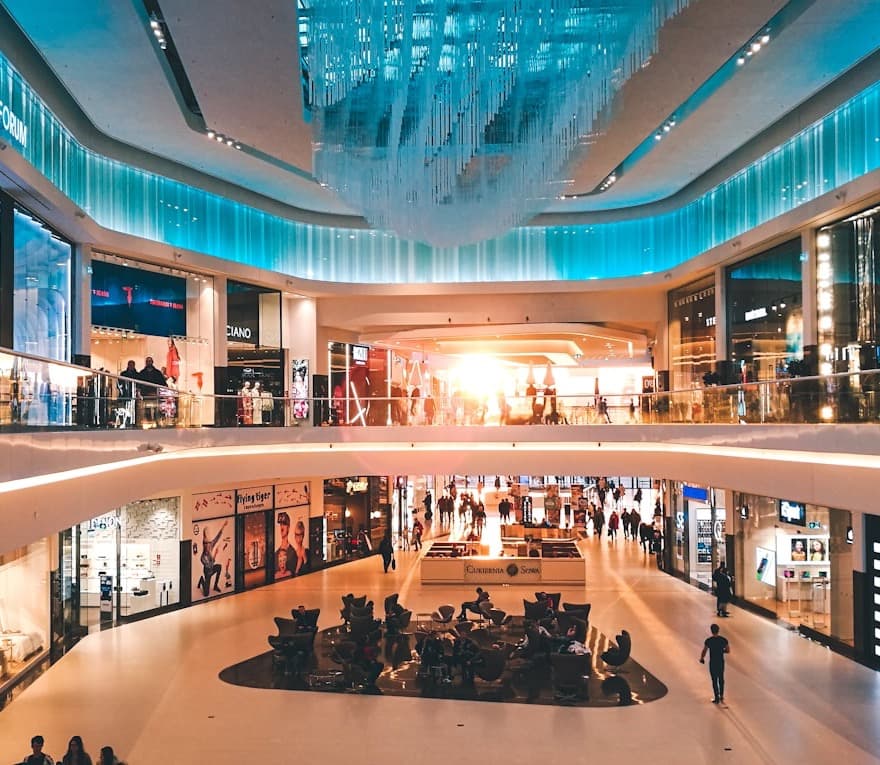 A mall atrium with a hanging light installation and shoppers already in the space