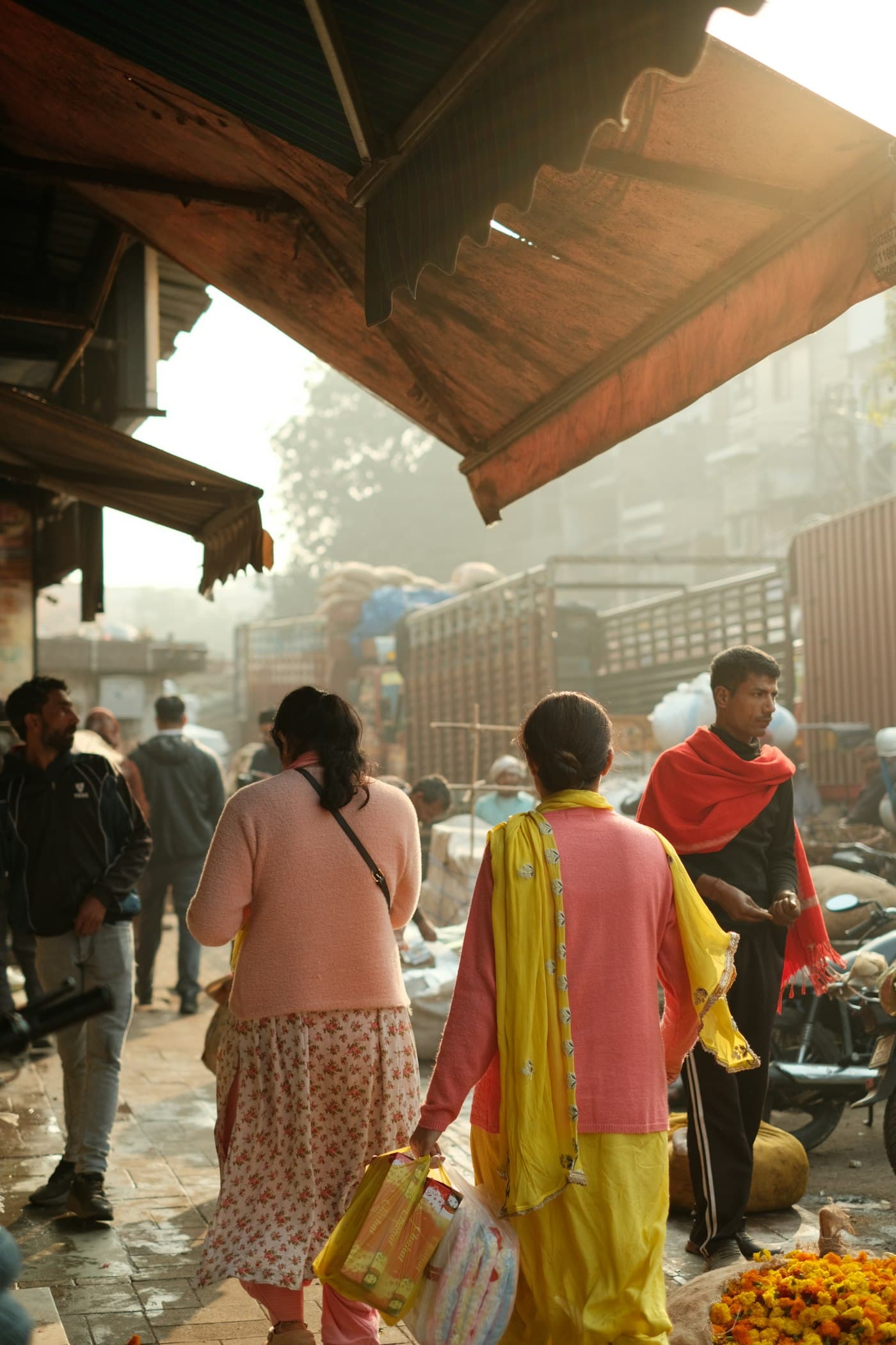 A local market street in warm light, shoppers walking between stalls