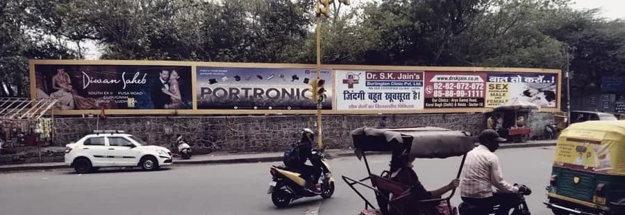 Traffic passing a run of roadside hoardings in Delhi